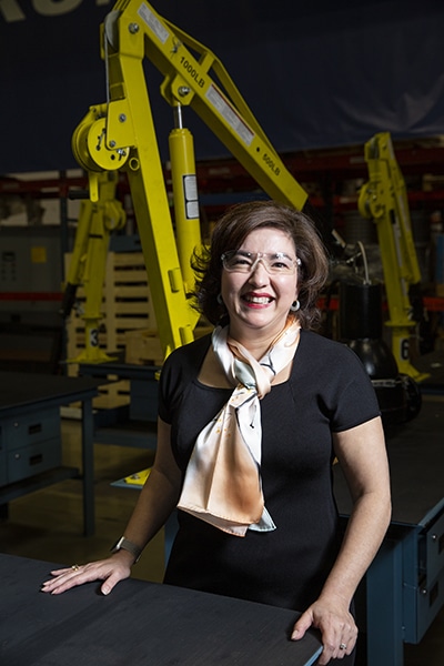 Rebecca O'Mara, Grundfos, seated in front of machinery, vertical image