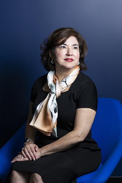Rebecca O'Mara, Grundfos, seated blue chair and backdrop, vertical portrait image