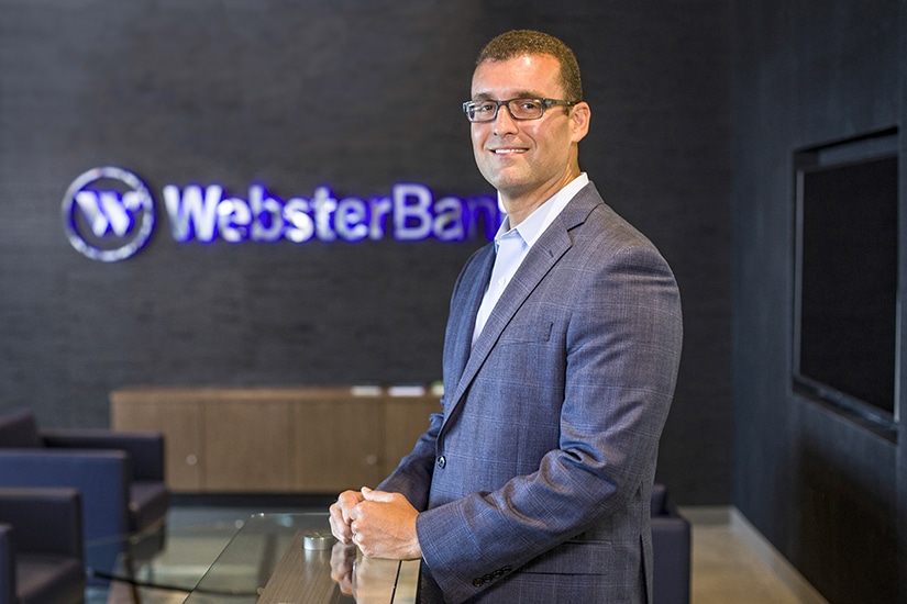 Jason Soto, Chief Credit Officer, Webster Bank, portrait by logo
