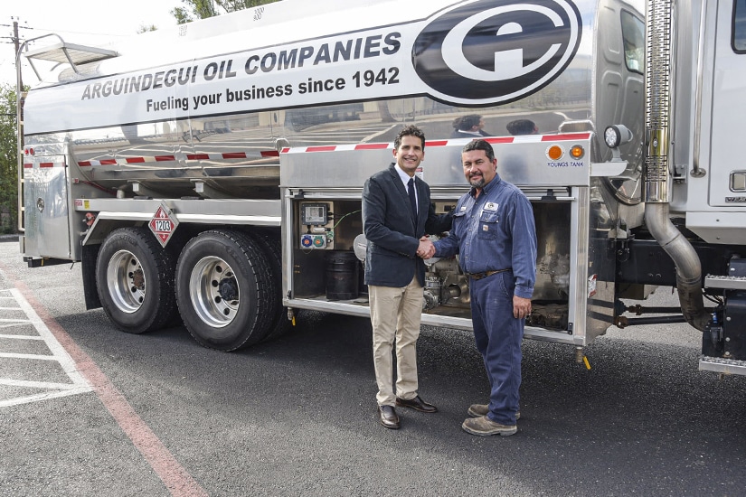 Alfonso Arguindegui Leyendecker shakign hands with employee in front of oil truck