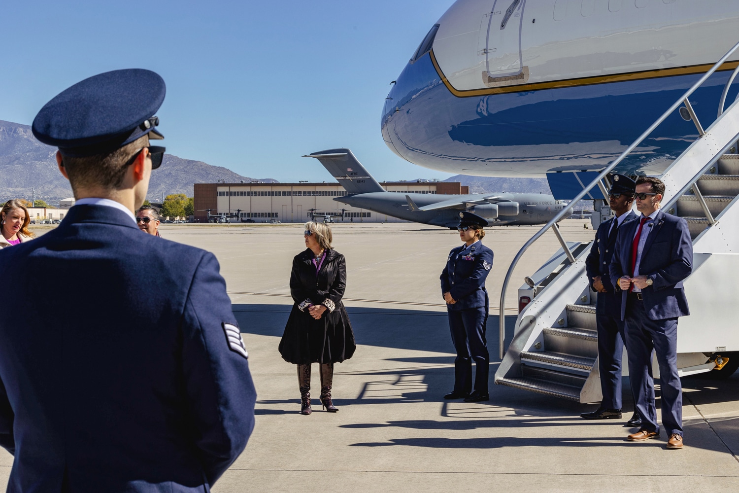 Air Force officers, secret service agents, and New Mexico representatives await Vice President Kamala Harris’s descent from Air Force Two