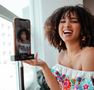 An Afro-Latina woman holds up her iphone to the camera while laughing
