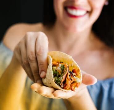 A woman cups an al pastor taco in her hands