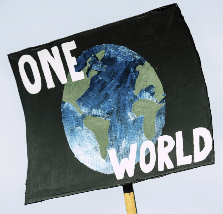 A picketing poster picturing the globe against a black background with the words "ONE WORLD" in white